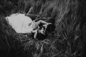 bride and groom lying in the grass on their wedding day