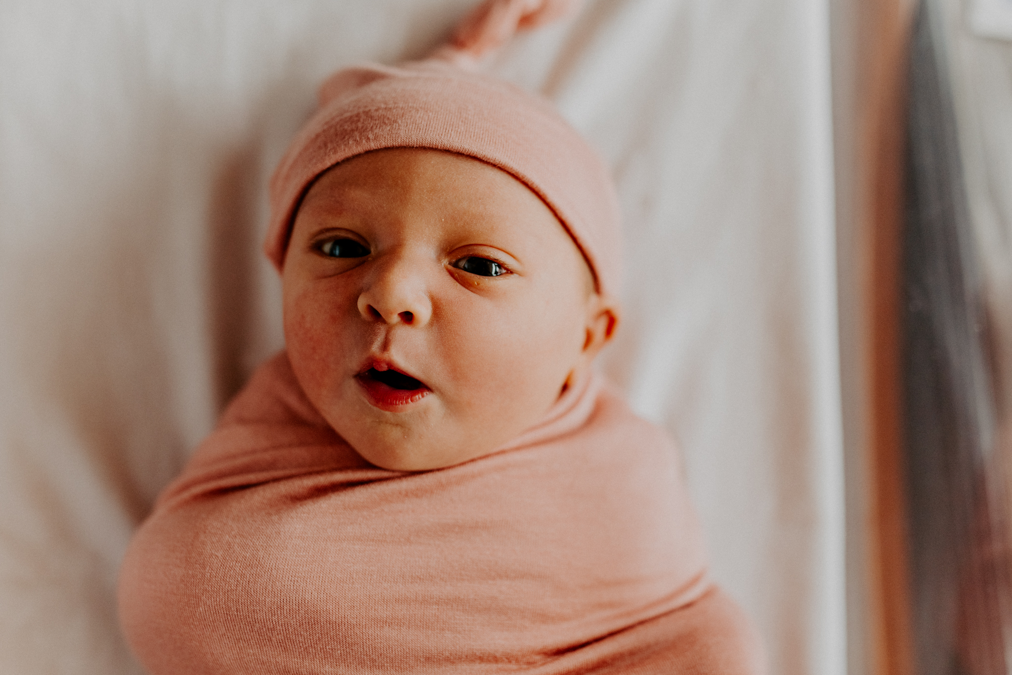 newborn baby girl with pink hat and swaddle